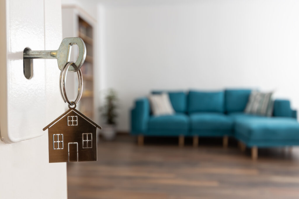 Open door to a new home. Door handle with key and home shaped keychain.